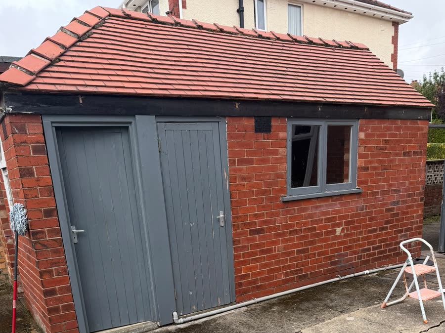 A garage roofline before work, with dark rotting timber fascia boards