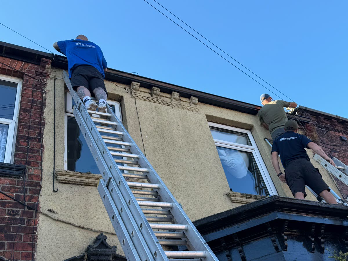 The Scarborough Seamless Guttering team fitting a new gutter run from ladders on a terraced house