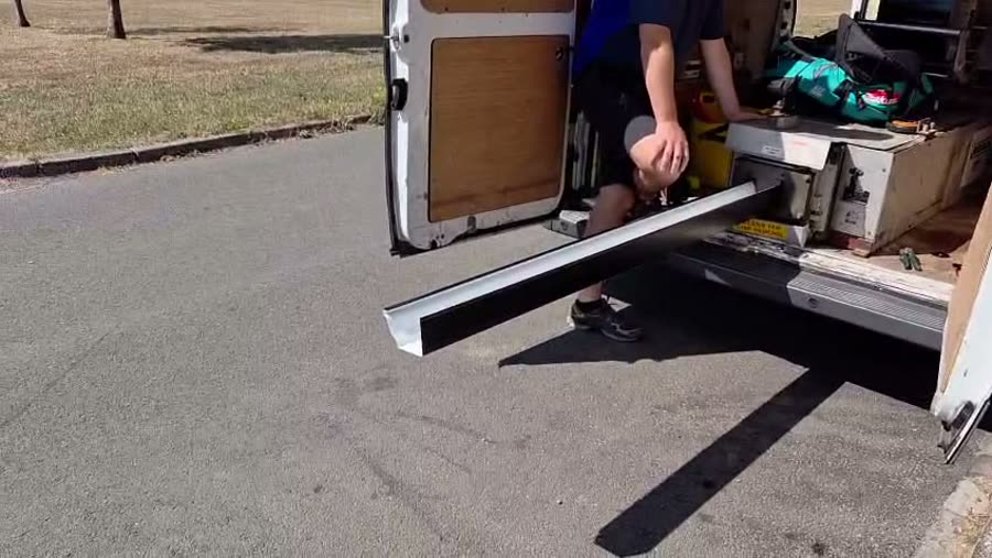 The roll-forming machine in the back of the van producing a continuous length of aluminium gutter
