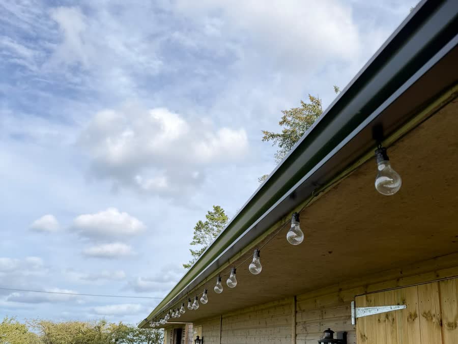 A full length run of black seamless guttering along a timber outbuilding